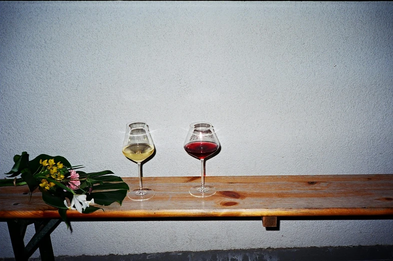 two glasses of wine are on a wooden table