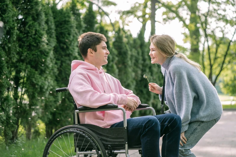 a man in a wheelchair talking to a girl