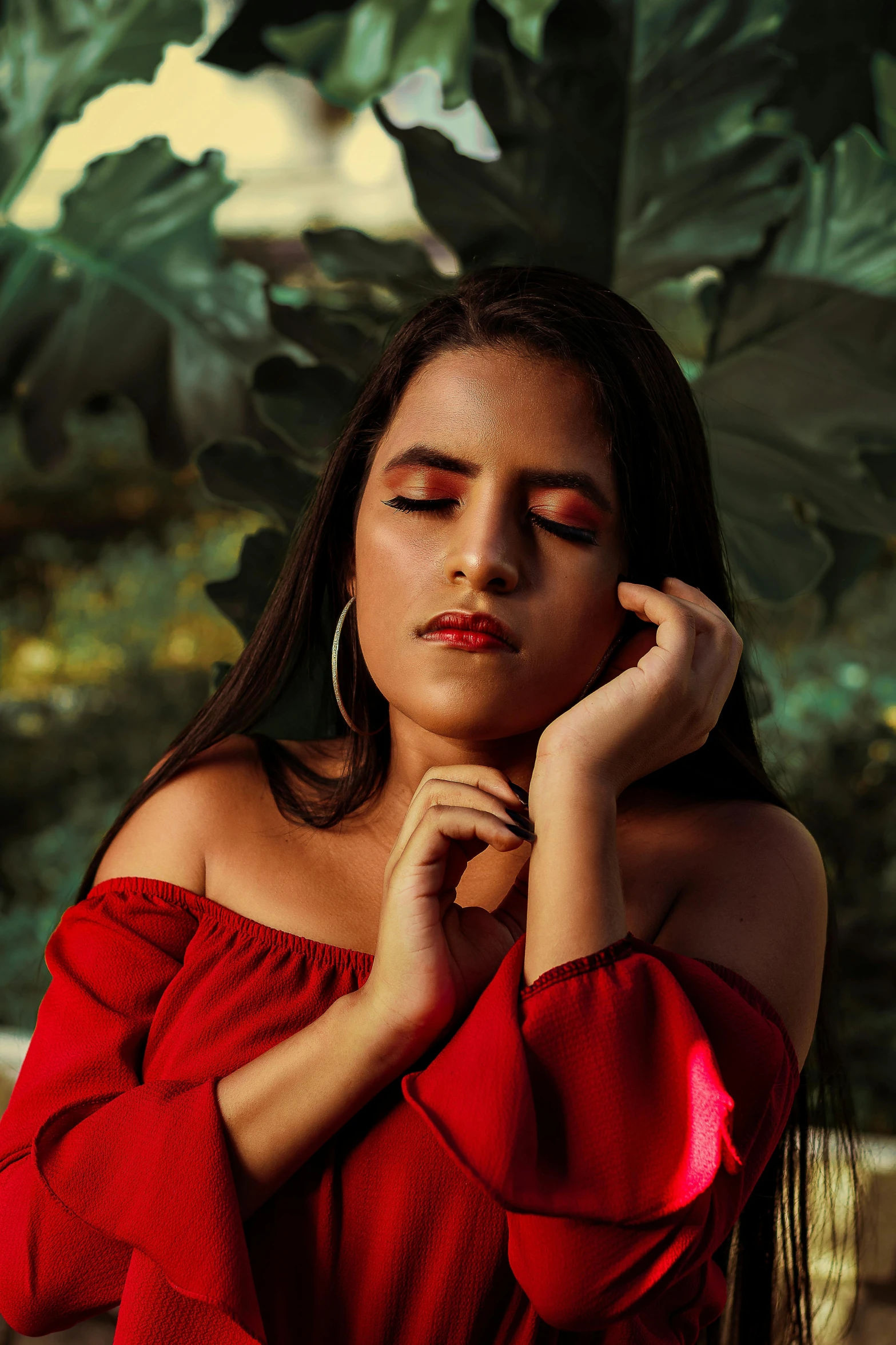 a woman poses for the camera with long dark hair and red blouse