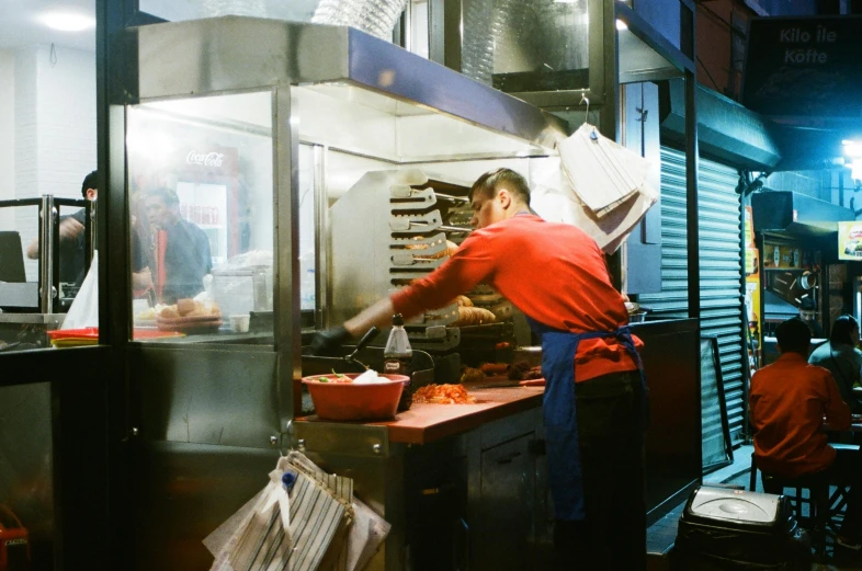 man preparing food at counter in kitchen with large amount of dishes