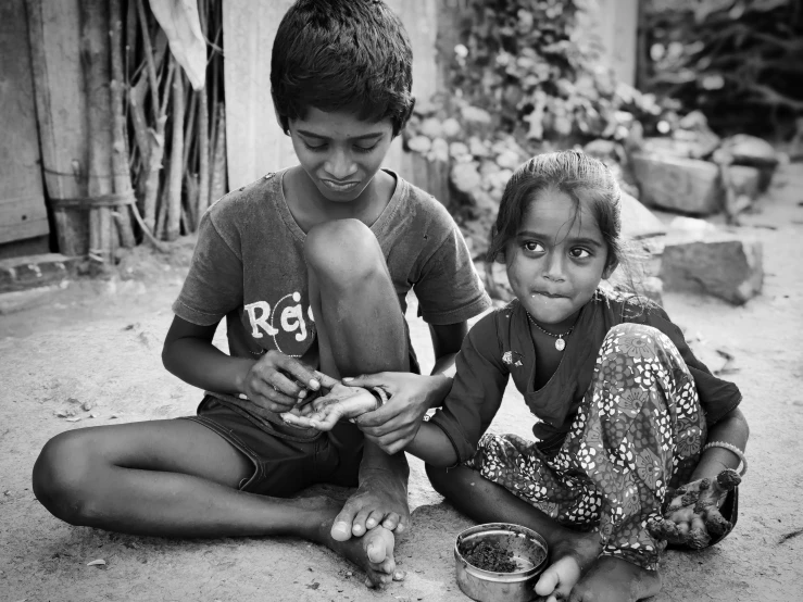 a boy and girl sitting on the ground