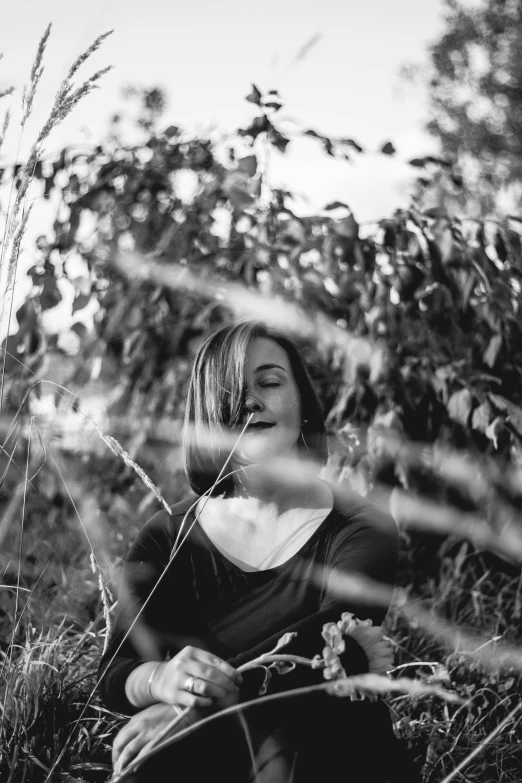 a woman sitting down in tall grass blowing wind