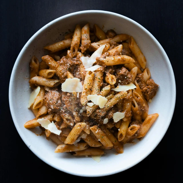 a bowl filled with pasta with meat, cheese and spices