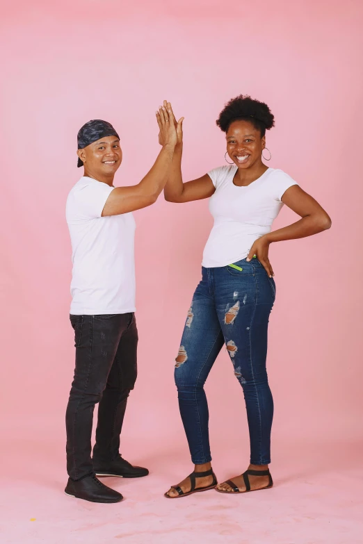 man and woman high - fiving each other with their hands raised