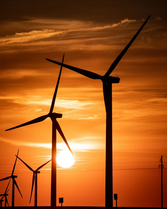 many windmills at sunset on a cloudy day