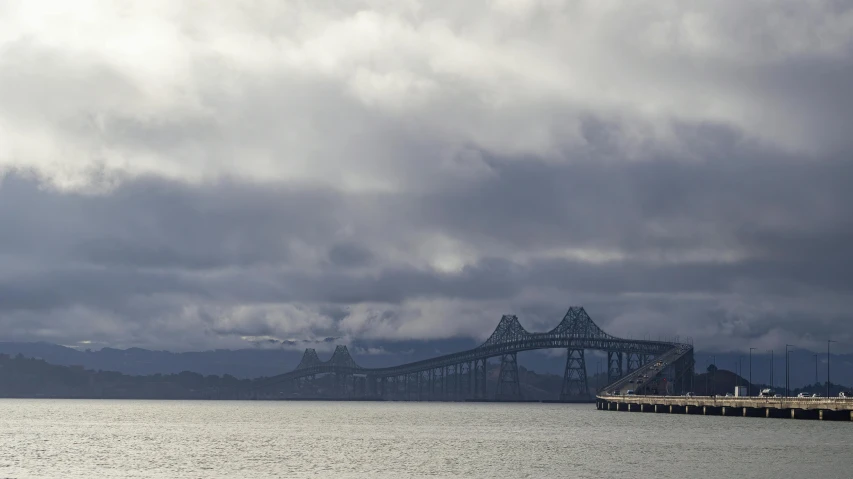 some clouds and water some hills and a large bridge