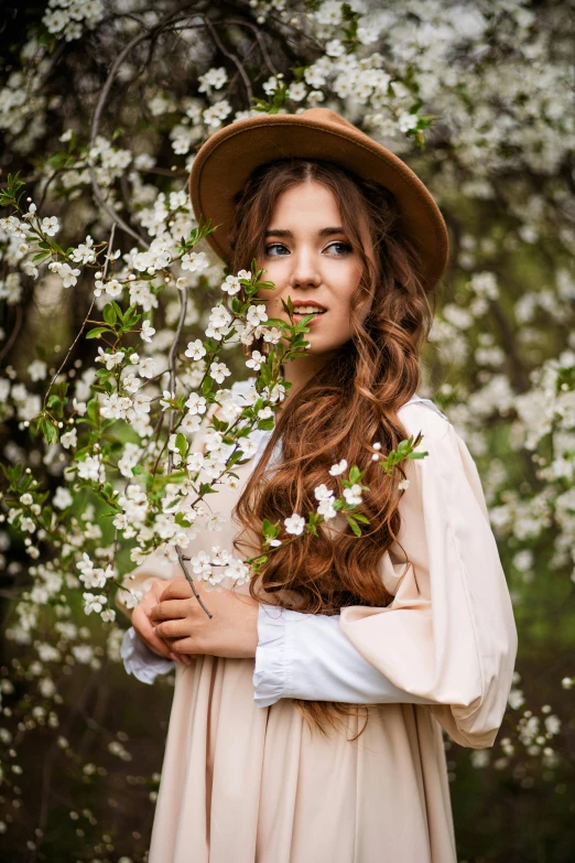 a girl in a bonnet holding flowers is posing for the camera