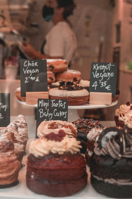 a display behind glass in a bakery filled with lots of cakes and pastries