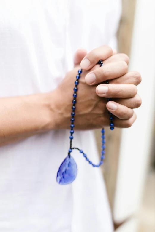 a hand holding a string of beads that has a blue bead around it