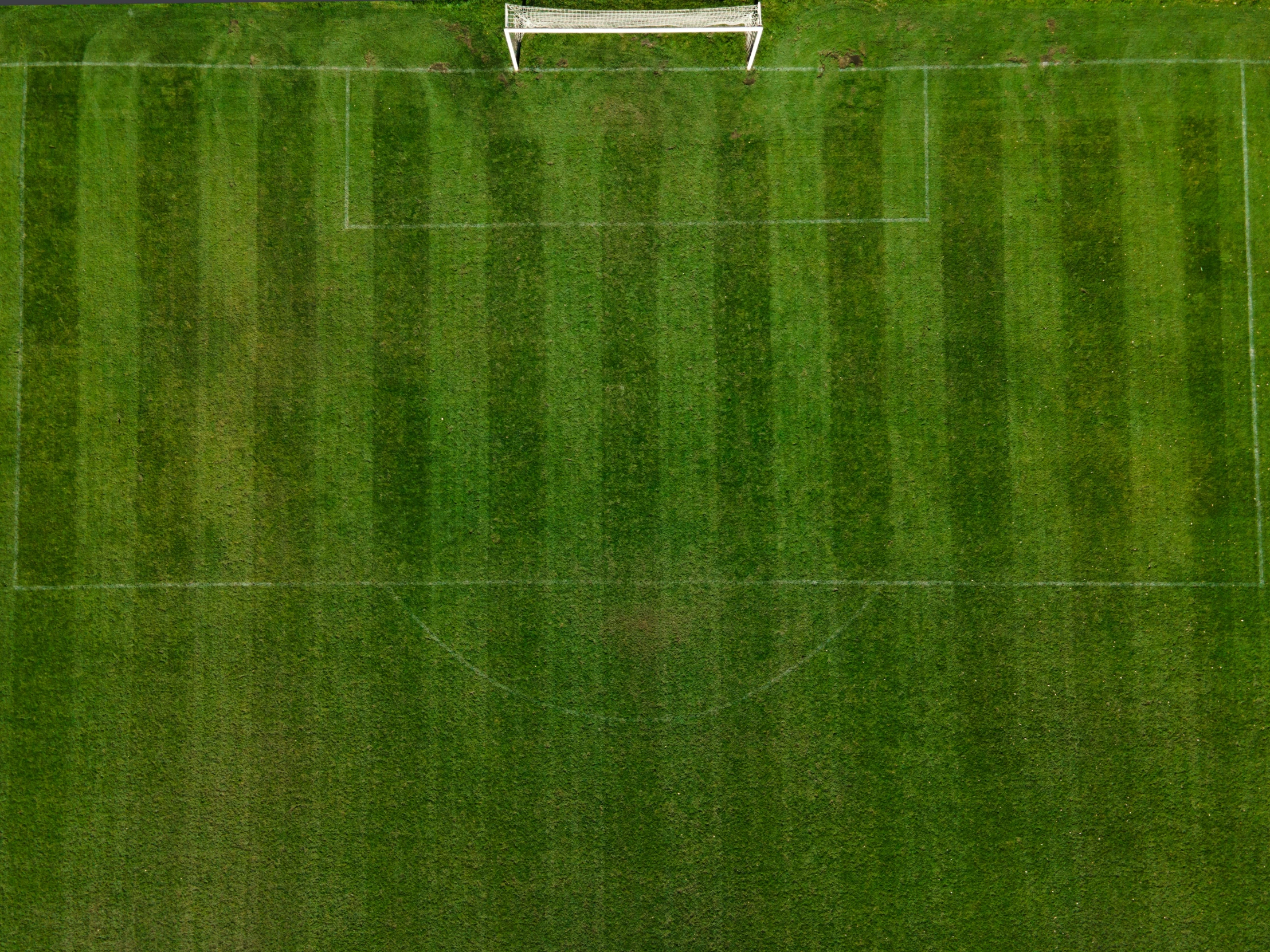 an overhead view of a soccer field with a white bench