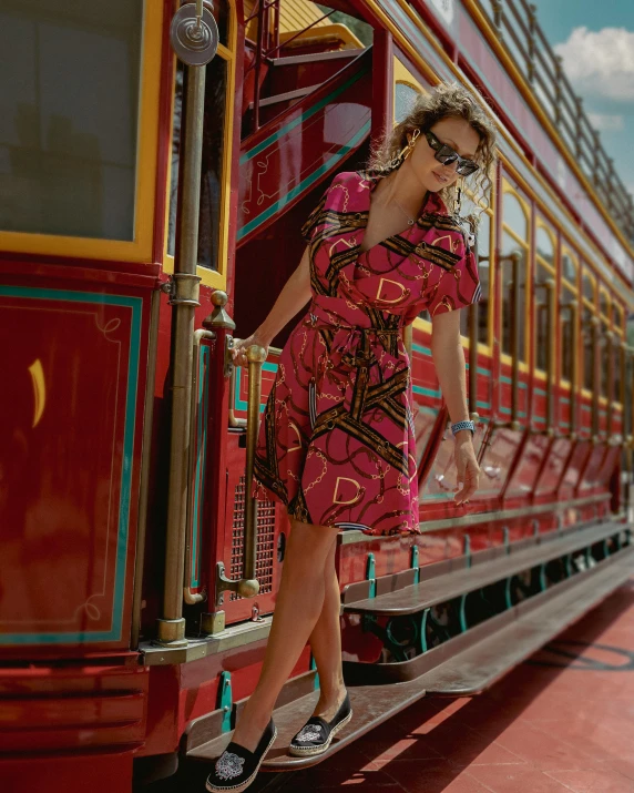 a girl in a red dress leaning out of a train window