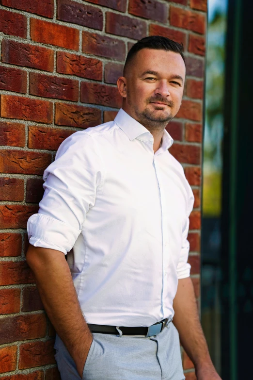 a man leans against the side of a brick building