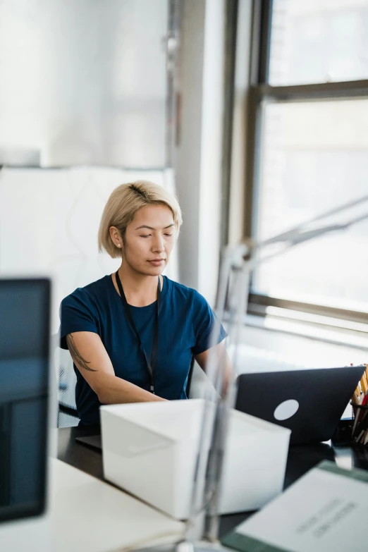 a woman is sitting at a table working on her computer