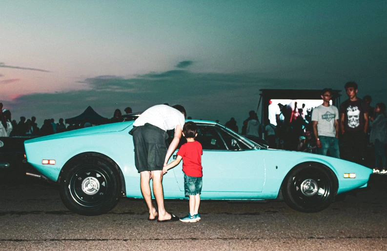 the family stands outside with a vintage car in front of them