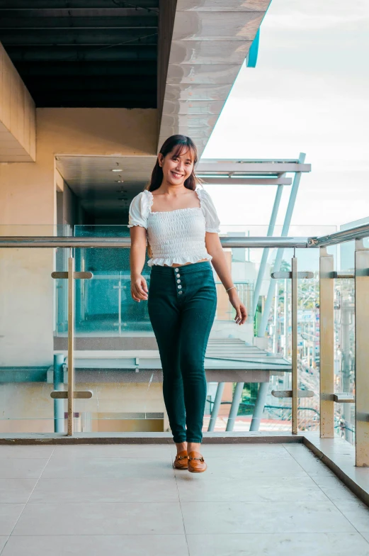 a smiling woman walks along the balcony near a metal railing