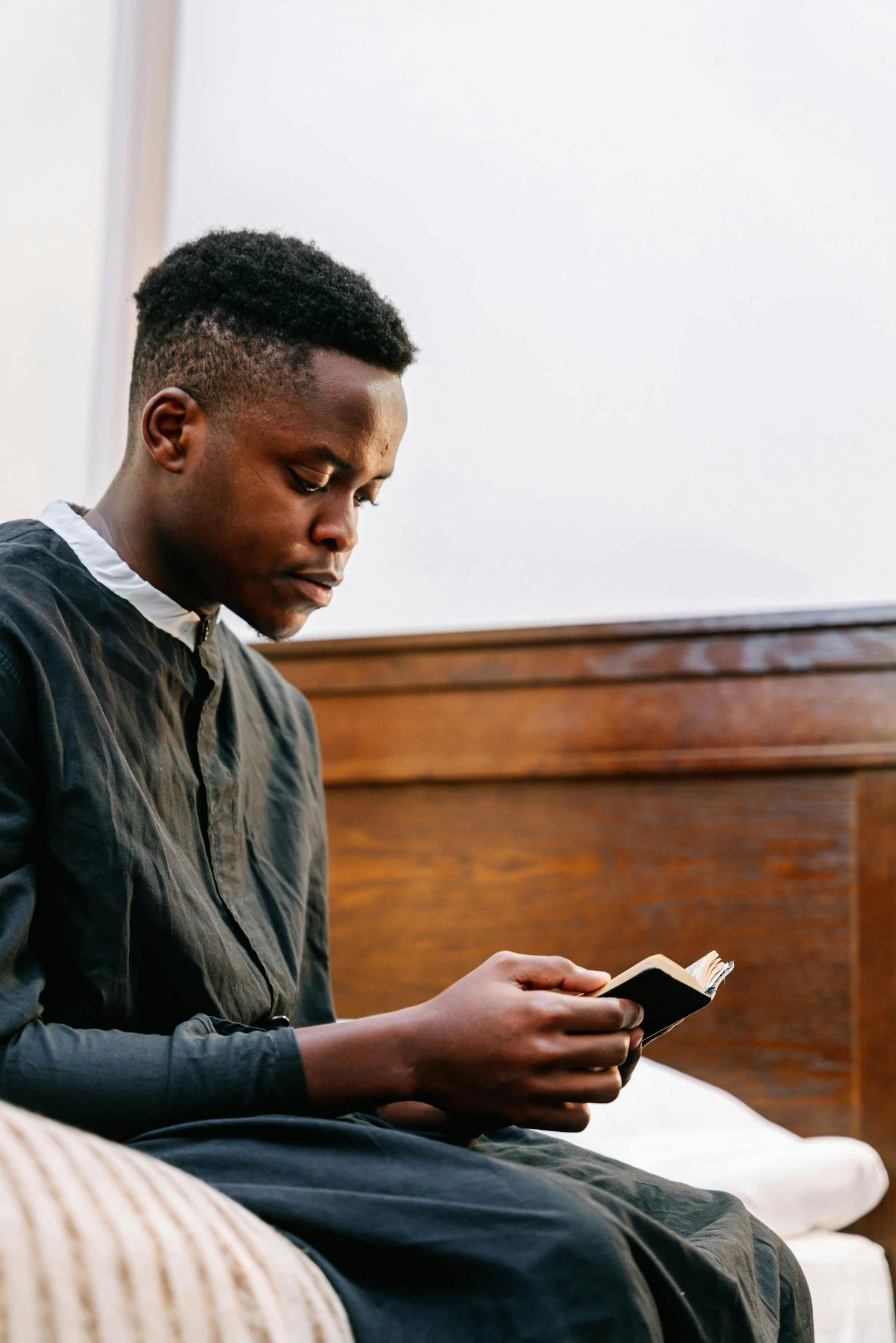 a young man sitting on a bed with a book in his hands