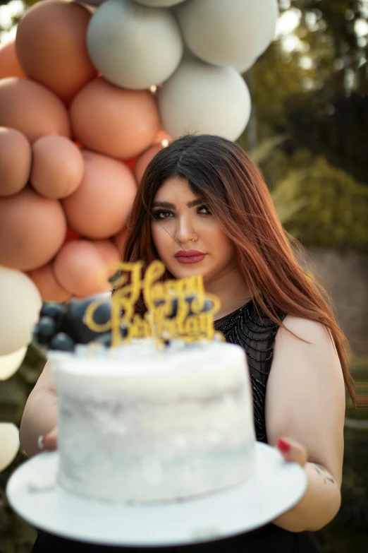 a beautiful young lady holding a white cake and a balloon