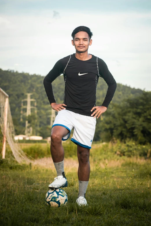 a man in shorts and socks is posing with a soccer ball