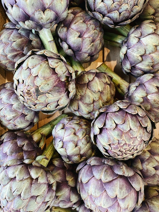 a bunch of fresh artichokes sit in a pile