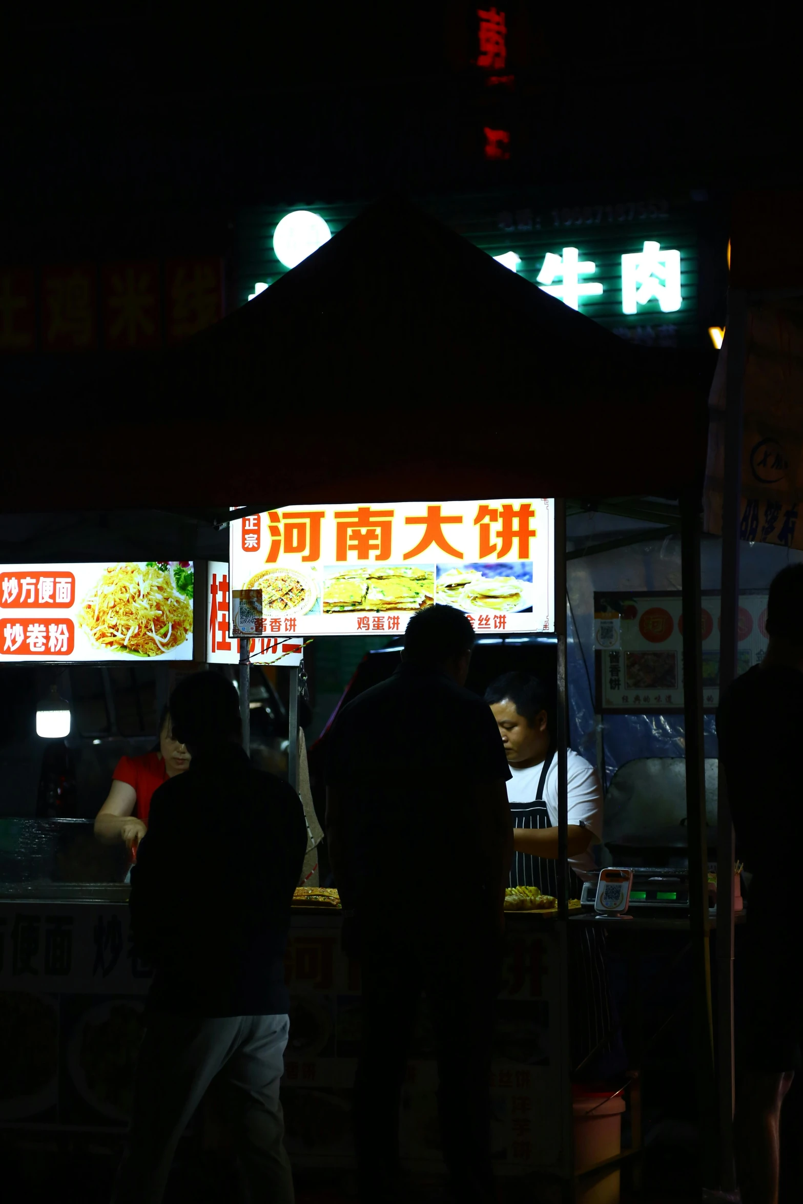 some people are standing under a hut at night