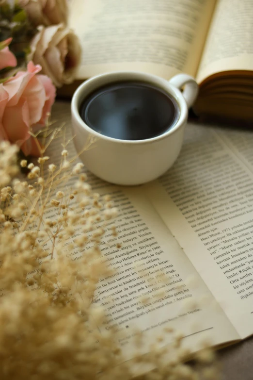 a cup of coffee on top of a book and flowers