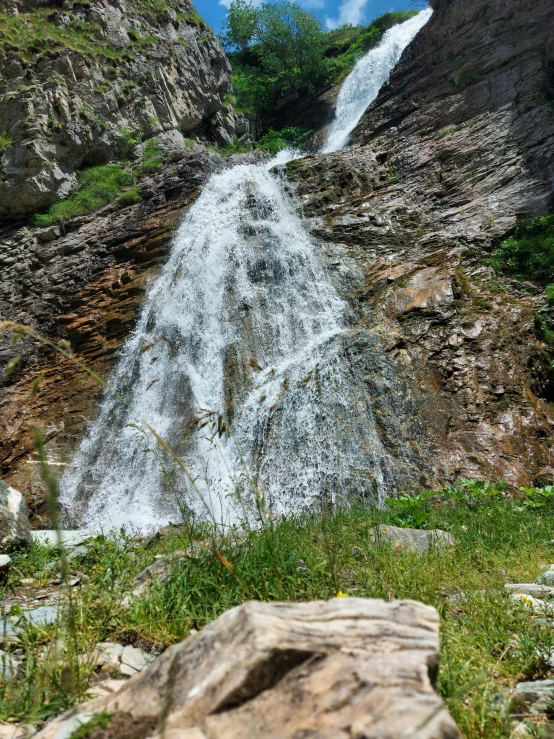 the water fall next to the rocky hill