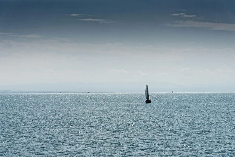 a lone boat sailing on the water in the blue