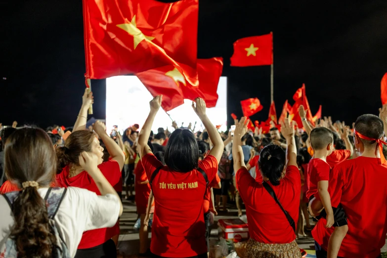 red workers wave flags in front of an audience