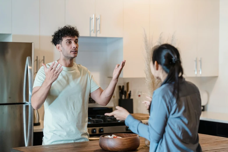 man and woman in kitchen with hand gesture at food bowl