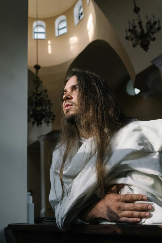 a young man with long hair sitting in a pew