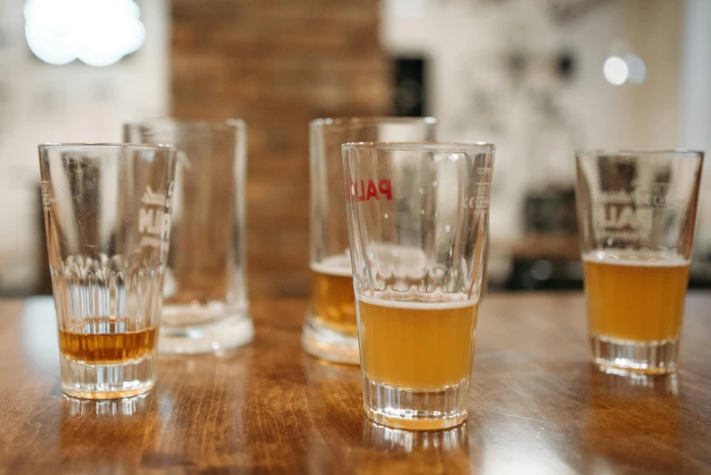 three glasses filled with liquid on top of a wooden table