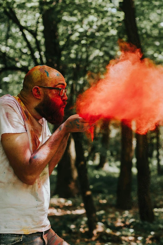 a man holding onto a bright red substance while standing in the woods