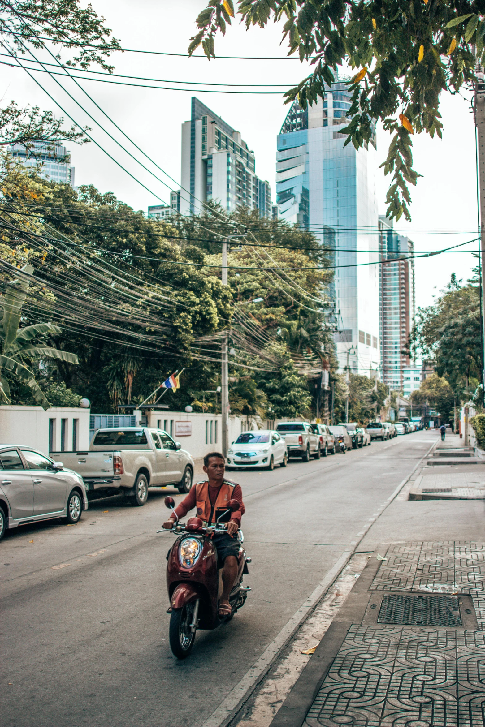 a man riding on the back of a red motorcycle down a street