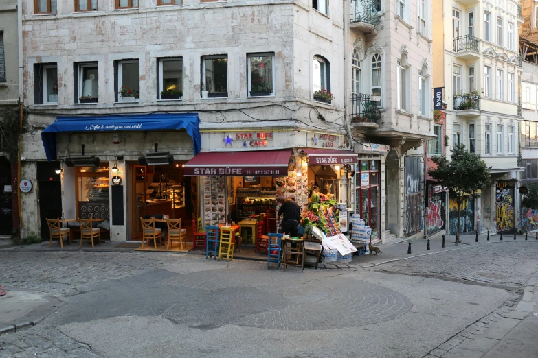 a man is standing outside of a building with several tables and chairs