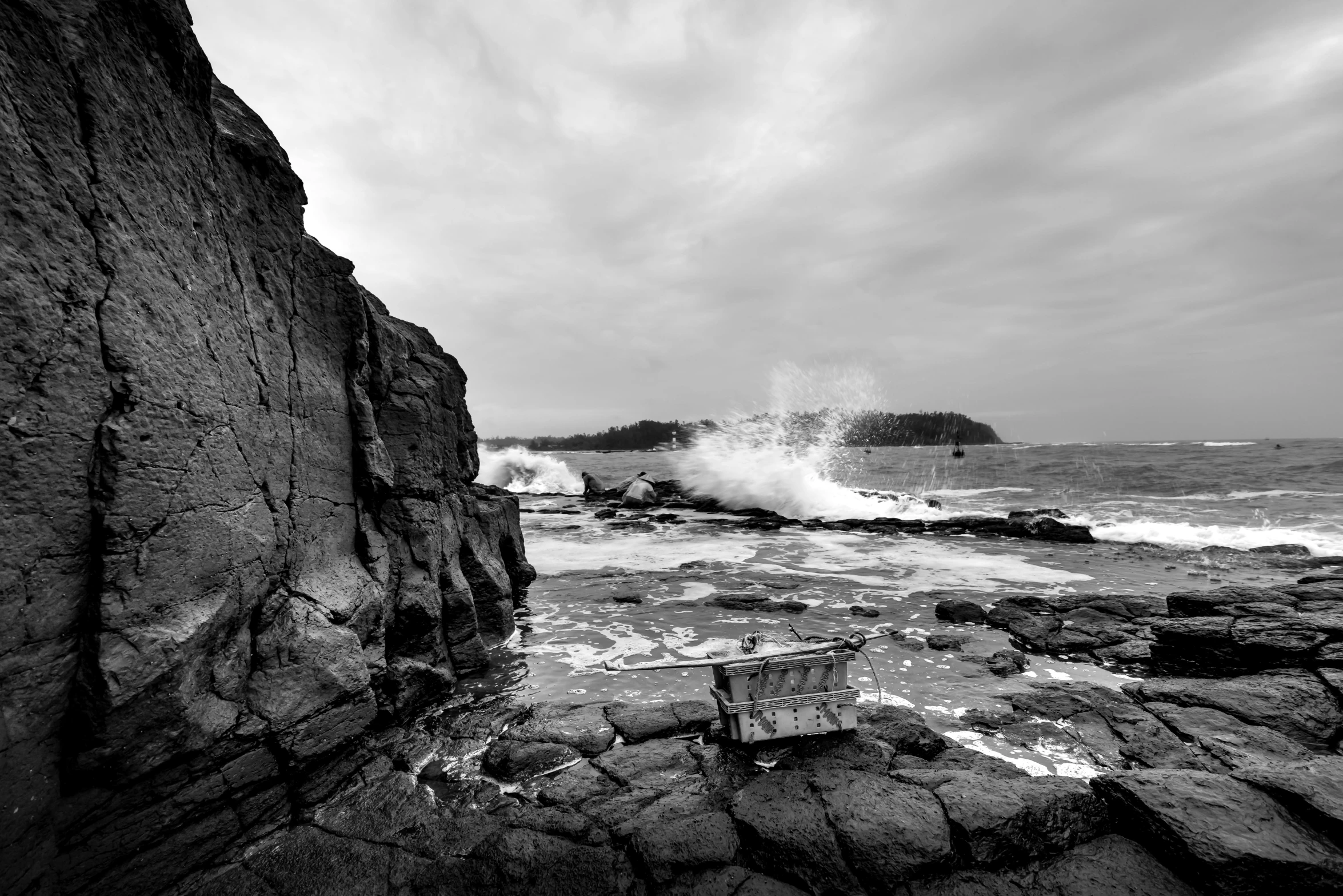 a black and white po of a wave crashing into the shore