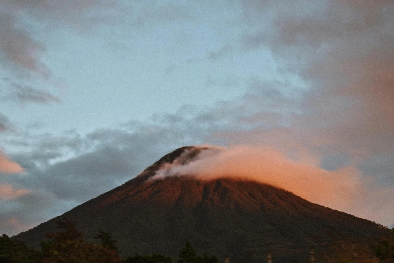 a mountain covered in clouds during the dusk