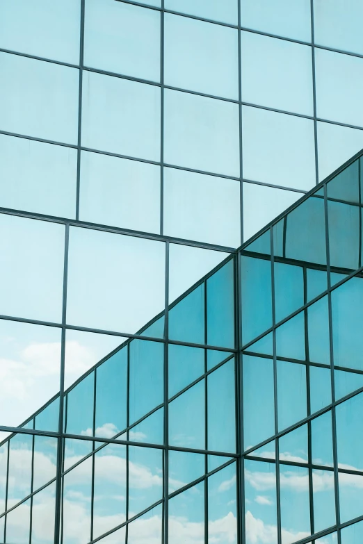 the exterior of a glass building with sky reflected in it