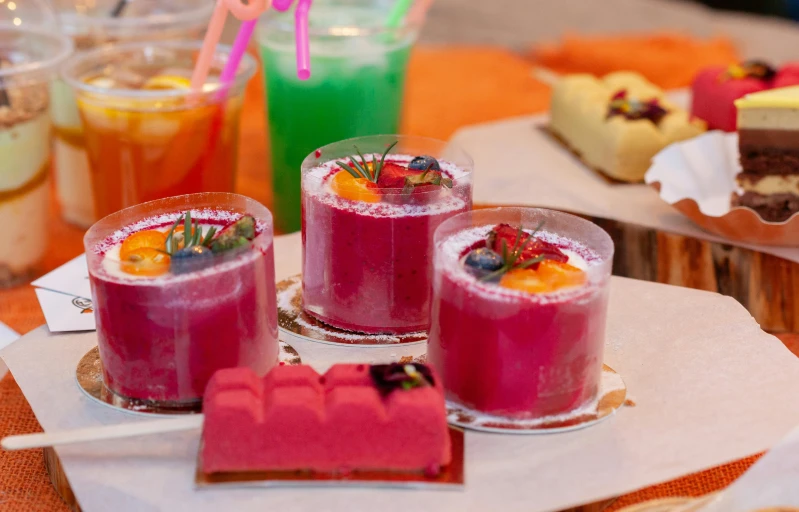 four glasses filled with drinks and desserts sitting on a table