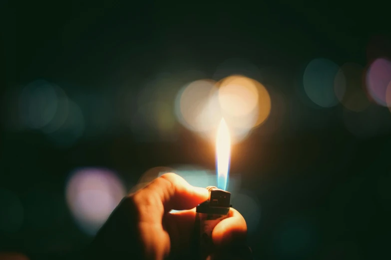 person holding a small lighter in the dark