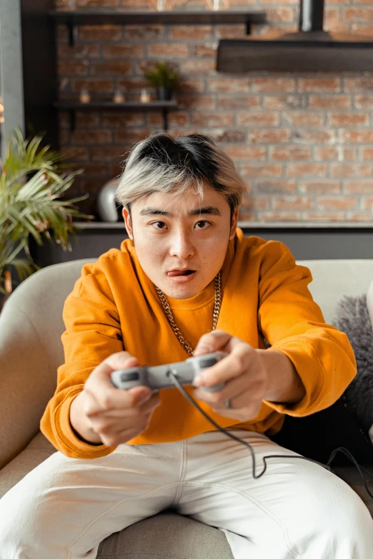 the young man sits on a couch with a remote control