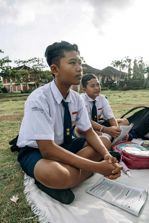 some young people sitting in the grass and looking at soing