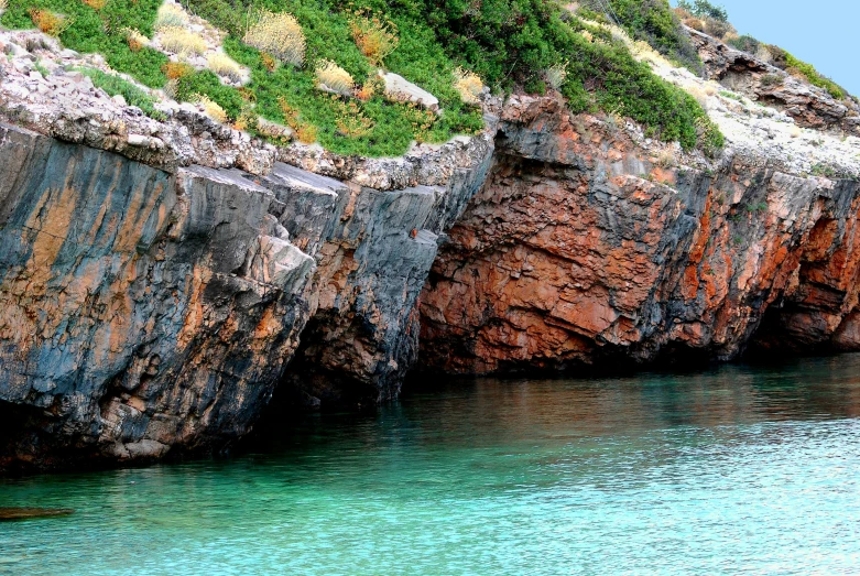 a person is standing near some cliffs and a body of water