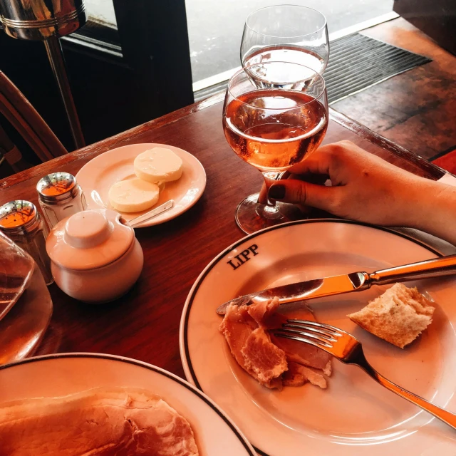 two plates and a glass filled with wine on a wooden table