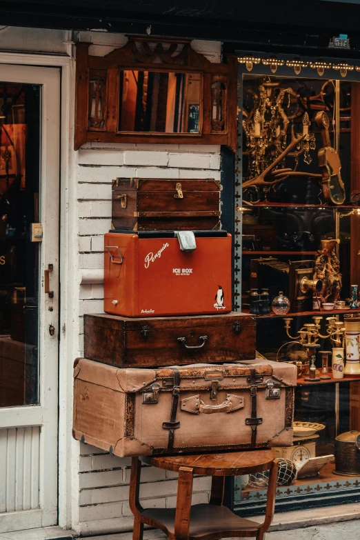 antique suitcases are piled together outside of a shop window