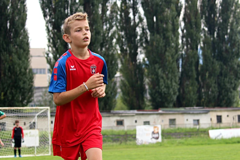 the boy in the red soccer uniform is looking back