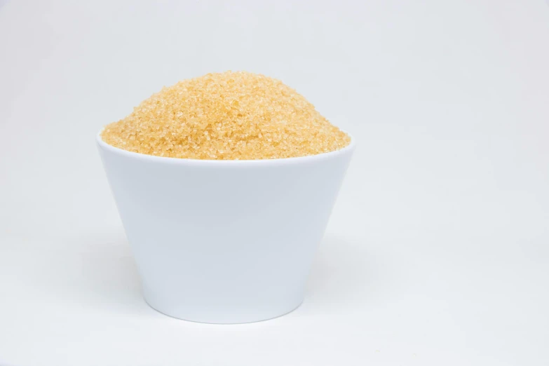 a round bowl filled with sugar on a white background