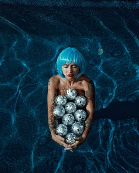a person floating in the water while holding metal balls