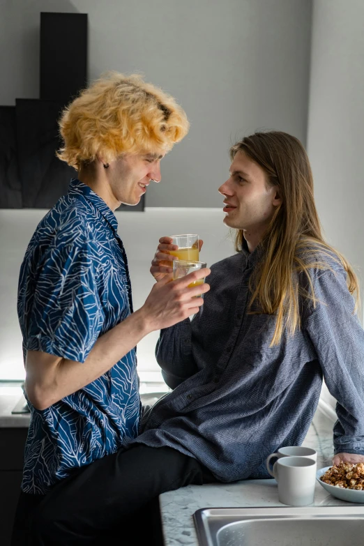 the young couple is sharing a drink in the kitchen