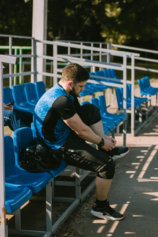 a man sitting on a bench next to blue chairs