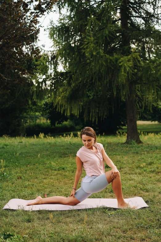 a woman in grey shorts sitting on a yoga mat